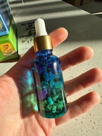 a hand holding a blue bottle with a blue flower in it