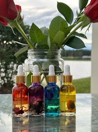 four bottles of essential oils on a table next to a vase of roses