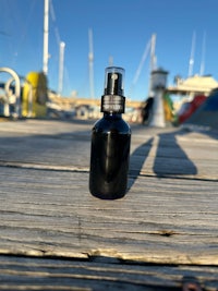 a bottle sitting on a dock with boats in the background